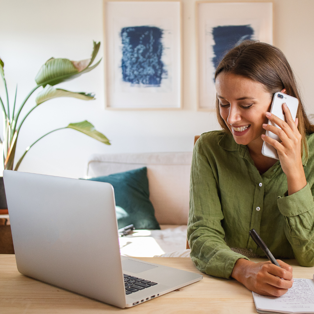 Woman on phone smiling with laptop