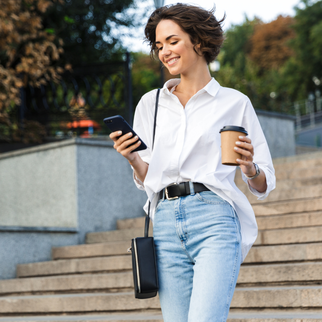 Woman smiling looking at phone with coffee cup